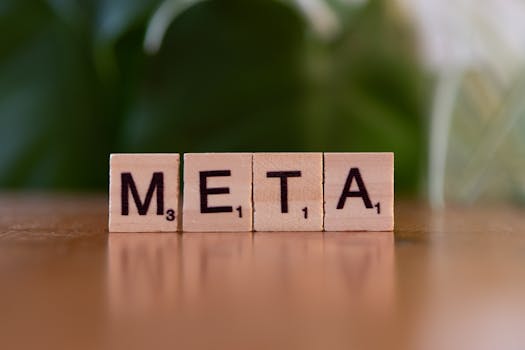 Wooden letter blocks spell META on a table with a blurred green background.